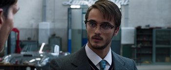 Movie still from “Lamborghini: The Man Behind the Legend” (2022), directed by Bobby Moresco – A man in a suit and tie wearing glasses; Close Up shot, Low angle