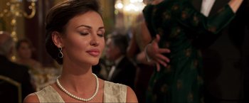 Movie still from “Lamborghini: The Man Behind the Legend” (2022), directed by Bobby Moresco – A beautiful woman wearing a pearl necklace and a white dress; Close Up shot, Over the shoulder angle