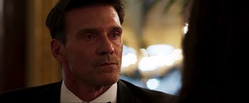 Movie still from “Lamborghini: The Man Behind the Legend” (2022), directed by Bobby Moresco – A person wearing a suit and tie; Close Up shot, Over the shoulder angle