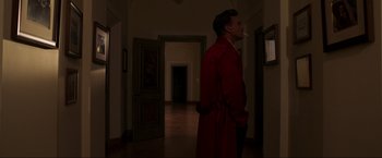 Movie still from “Lamborghini: The Man Behind the Legend” (2022), directed by Bobby Moresco – A man smoking a cigarette while wearing a red robe; Medium shot, Over the shoulder angle
