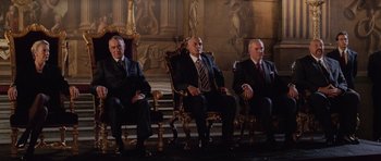 Movie still from “Lara Croft: Tomb Raider” (2001), directed by Simon West – A group of men sitting on top of a wooden chair; Wide shot, Low angle