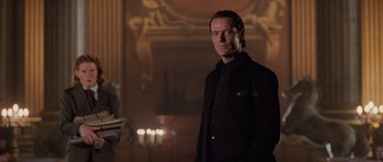 Movie still from “Lara Croft: Tomb Raider” (2001), directed by Simon West – A man standing in a dark room with candles in front of him; Medium shot, Low angle