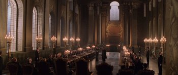 Movie still from “Lara Croft: Tomb Raider” (2001), directed by Simon West – People are sitting at a long table in a large room; Extreme Wide shot, High angle