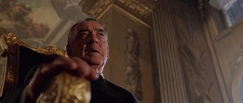 Movie still from “Lara Croft: Tomb Raider” (2001), directed by Simon West – An older man is holding something in his hand; Close Up shot, Low angle