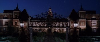 Movie still from “Lara Croft: Tomb Raider” (2001), directed by Simon West – A gate leading to a building at night with a clock tower; Extreme Wide shot, Low angle