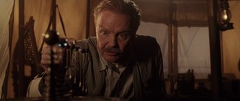 Movie still from “Lara Croft: Tomb Raider” (2001), directed by Simon West – An older man is looking at the camera; Close Up shot, Low angle