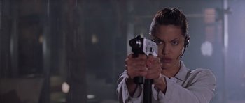 Movie still from “Lara Croft: Tomb Raider” (2001), directed by Simon West – A woman is holding a gun in her hands; Close Up shot, Low angle