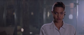 Movie still from “Lara Croft: Tomb Raider” (2001), directed by Simon West – A woman in a white shirt is looking at the camera; Close Up shot, Over the shoulder angle