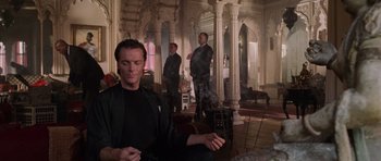 Movie still from “Lara Croft: Tomb Raider” (2001), directed by Simon West – A man sitting in the middle of a room with his eyes closed; Medium shot, Low angle