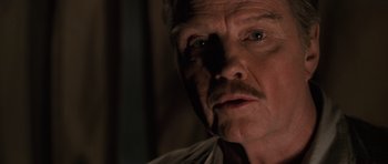 Movie still from “Lara Croft: Tomb Raider” (2001), directed by Simon West – An older man with a mustache looking at the camera; Close Up shot, Low angle