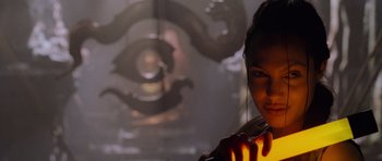 Movie still from “Lara Croft: Tomb Raider” (2001), directed by Simon West – A woman is holding a light in her hand; Close Up shot, Over the shoulder angle