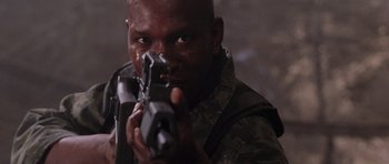 Movie still from “Lara Croft: Tomb Raider” (2001), directed by Simon West – A man holding a gun while standing in a room; Close Up shot, Low angle
