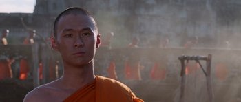Movie still from “Lara Croft: Tomb Raider” (2001), directed by Simon West – A man in an orange robe standing in front of a crowd; Close Up shot, Low angle
