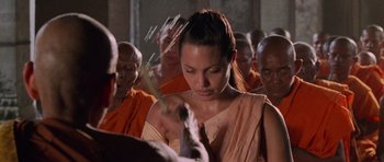 Movie still from “Lara Croft: Tomb Raider” (2001), directed by Simon West – A group of people gathered around a woman in orange; Close Up shot, Over the shoulder angle