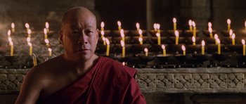 Movie still from “Lara Croft: Tomb Raider” (2001), directed by Simon West – A man in a red robe sitting in front of candles; Close Up shot, Low angle