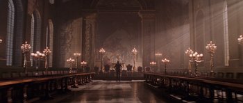 Movie still from “Lara Croft: Tomb Raider” (2001), directed by Simon West – A man standing in front of a room filled with chandeliers; Extreme Wide shot, Low angle