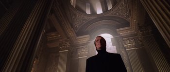 Movie still from “Lara Croft: Tomb Raider” (2001), directed by Simon West – A man standing in front of an ornate ceiling; Medium shot, Low angle