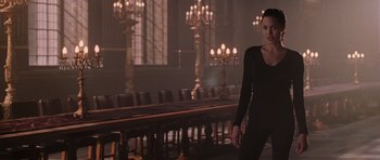 Movie still from “Lara Croft: Tomb Raider” (2001), directed by Simon West – A woman standing in front of a long dining table; Medium shot, Low angle