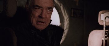 Movie still from “Lara Croft: Tomb Raider” (2001), directed by Simon West – An older man in a black jacket looking at the camera; Close Up shot, Low angle