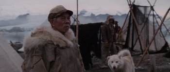 Movie still from “Lara Croft: Tomb Raider” (2001), directed by Simon West – An old man and a white dog are standing together; Medium shot, Over the shoulder angle
