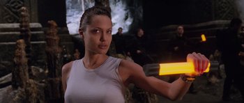 Movie still from “Lara Croft: Tomb Raider” (2001), directed by Simon West – A woman is holding a gun in her hand; Close Up shot, Over the shoulder angle