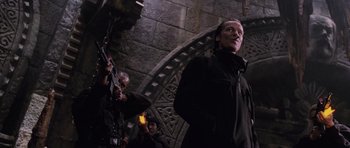 Movie still from “Lara Croft: Tomb Raider” (2001), directed by Simon West – A man standing in front of a stone wall; Medium shot, Low angle