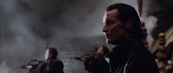 Movie still from “Lara Croft: Tomb Raider” (2001), directed by Simon West – A man with a gun in his hand is looking at something in the distance; Close Up shot, Low angle