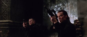 Movie still from “Lara Croft: Tomb Raider” (2001), directed by Simon West – A group of men standing next to each other holding guns; Medium shot, Low angle