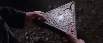 Movie still from “Lara Croft: Tomb Raider” (2001), directed by Simon West – Two hands holding a book with a light coming out of it; Extreme Close Up shot, Overhead angle