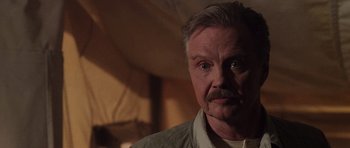 Movie still from “Lara Croft: Tomb Raider” (2001), directed by Simon West – An older man with a mustache and a goatee stares at the camera; Close Up shot, Over the shoulder angle