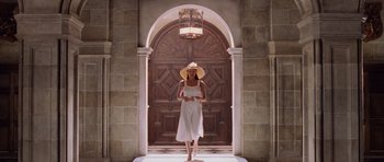 Movie still from “Lara Croft: Tomb Raider” (2001), directed by Simon West – A woman wearing a white dress and a straw hat standing in front of an archway; Wide shot, Low angle