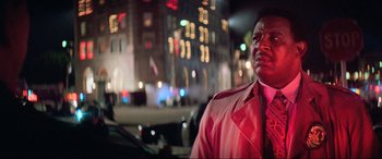 Movie still from “Last Action Hero” (1993), directed by John McTiernan – A man in a red jacket standing next to a car; Close Up shot, Low angle