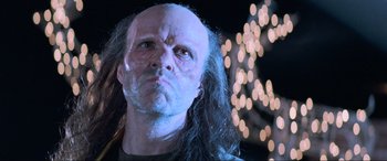 Movie still from “Last Action Hero” (1993), directed by John McTiernan – A person wearing a wig with lights in the background; Close Up shot, Low angle