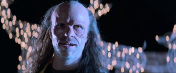 Movie still from “Last Action Hero” (1993), directed by John McTiernan – An old man with long hair and a bald head; Close Up shot, Low angle