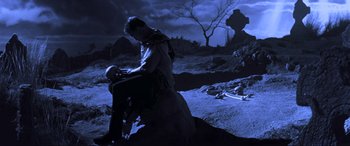 Movie still from “Last Action Hero” (1993), directed by John McTiernan – A man sitting on the ground in the middle of the night; Wide shot, Low angle