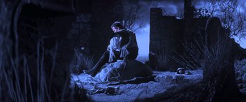 Movie still from “Last Action Hero” (1993), directed by John McTiernan – A man sitting on top of a rock in the middle of the night; Wide shot, Low angle