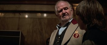 Movie still from “Last Action Hero” (1993), directed by John McTiernan – An older man wearing a suit and tie; Close Up shot, Low angle