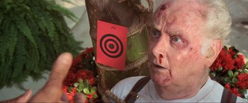 Movie still from “Last Action Hero” (1993), directed by John McTiernan – An old man with blood on his face and a target on the back of his head; Close Up shot, Over the shoulder angle
