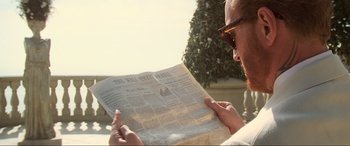 Movie still from “Last Action Hero” (1993), directed by John McTiernan – A man reading a newspaper outside in the sun; Close Up shot, Over the shoulder angle