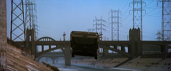 Movie still from “Last Action Hero” (1993), directed by John McTiernan – A car that is flying through the air over a bridge; Extreme Wide shot, Low angle