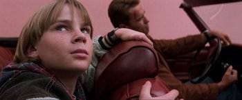 Movie still from “Last Action Hero” (1993), directed by John McTiernan – A man and a woman sitting next to each other on a couch; Close Up shot, Low angle