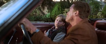 Movie still from “Last Action Hero” (1993), directed by John McTiernan – A man and a woman sitting in the back seat of a car; Close Up shot, Over the shoulder angle