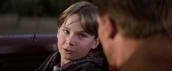 Movie still from “Last Action Hero” (1993), directed by John McTiernan – A young boy sitting next to another man; Close Up shot, Over the shoulder angle