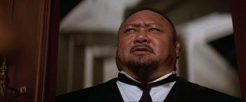 Movie still from “Last Action Hero” (1993), directed by John McTiernan – A person wearing a suit and tie; Close Up shot, Low angle