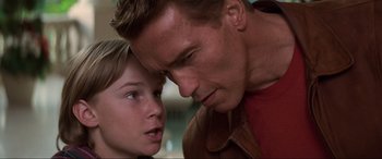 Movie still from “Last Action Hero” (1993), directed by John McTiernan – A man and a boy looking at one another; Close Up shot, Low angle