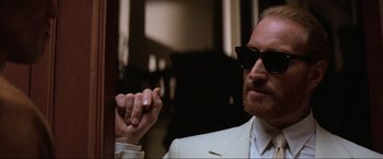 Movie still from “Last Action Hero” (1993), directed by John McTiernan – A person wearing sunglasses and holding a cigarette; Close Up shot, Low angle