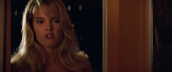 Movie still from “Last Action Hero” (1993), directed by John McTiernan – A woman with long blonde hair standing next to a door; Close Up shot, Over the shoulder angle