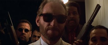 Movie still from “Last Action Hero” (1993), directed by John McTiernan – A person wearing a suit and sunglasses; Close Up shot, Low angle