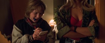 Movie still from “Last Action Hero” (1993), directed by John McTiernan – A young boy writing on a notepad next to a woman; Close Up shot, Over the shoulder angle