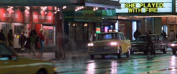 Movie still from “Last Action Hero” (1993), directed by John McTiernan – A taxi cab driving down a wet street at night; Extreme Wide shot, Low angle